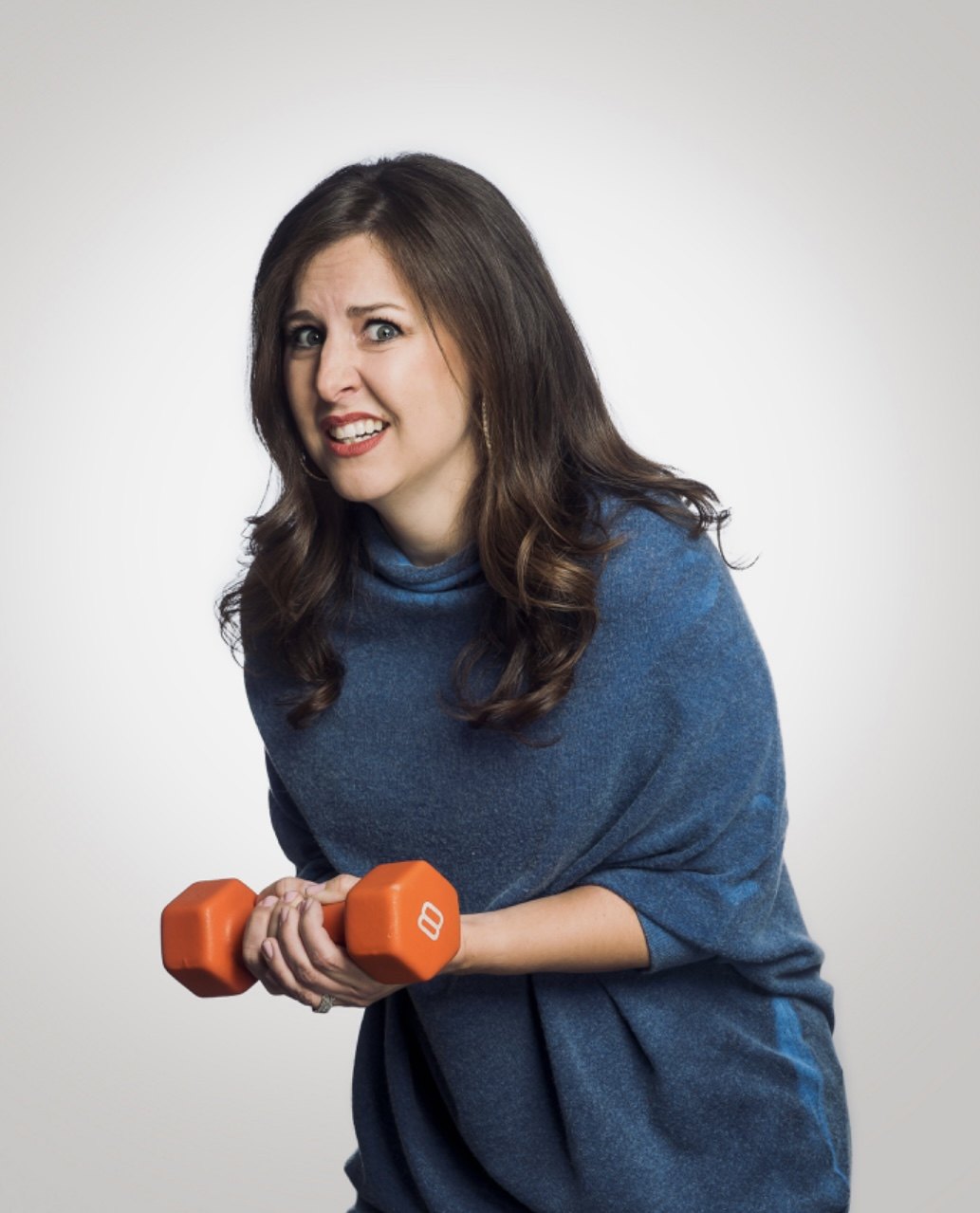 Emily playfully struggling to lift a small dumbbell